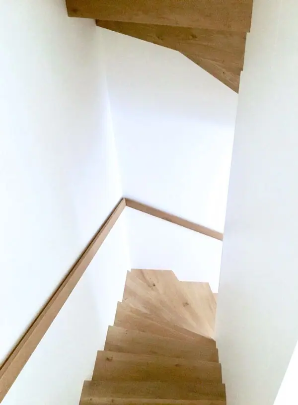 Treppe mit Eichenstufen und Handlauf vor weißer Wand
